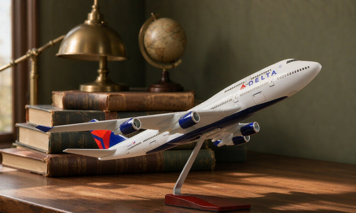 The 1/160 Delta Boeing 747 diecast model on its stand on a walnut desk beside aviation books and a globe