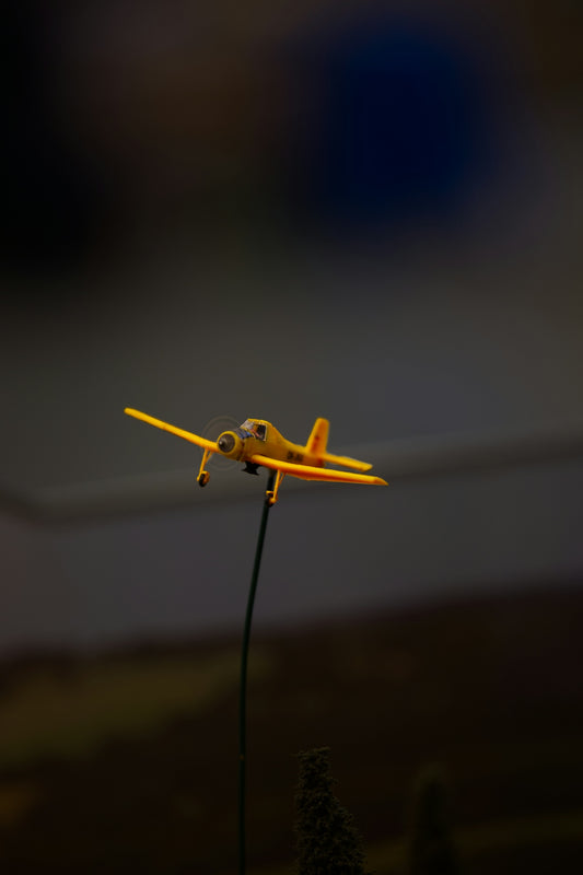 A small yellow airplane on a stick