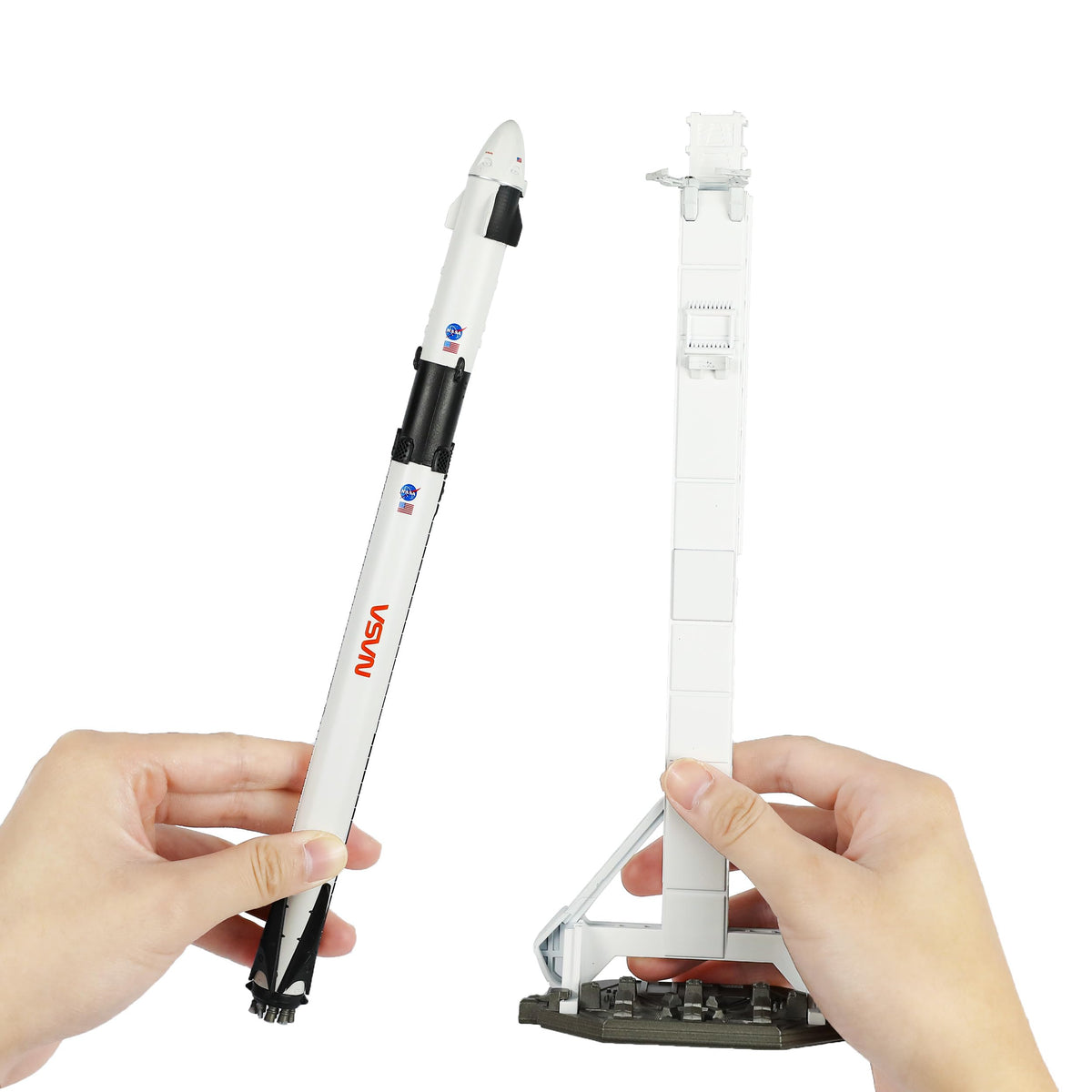 Hands holding a QIYUMOKE 1/200 SpaceX Starship rocket model and its white launch tower.