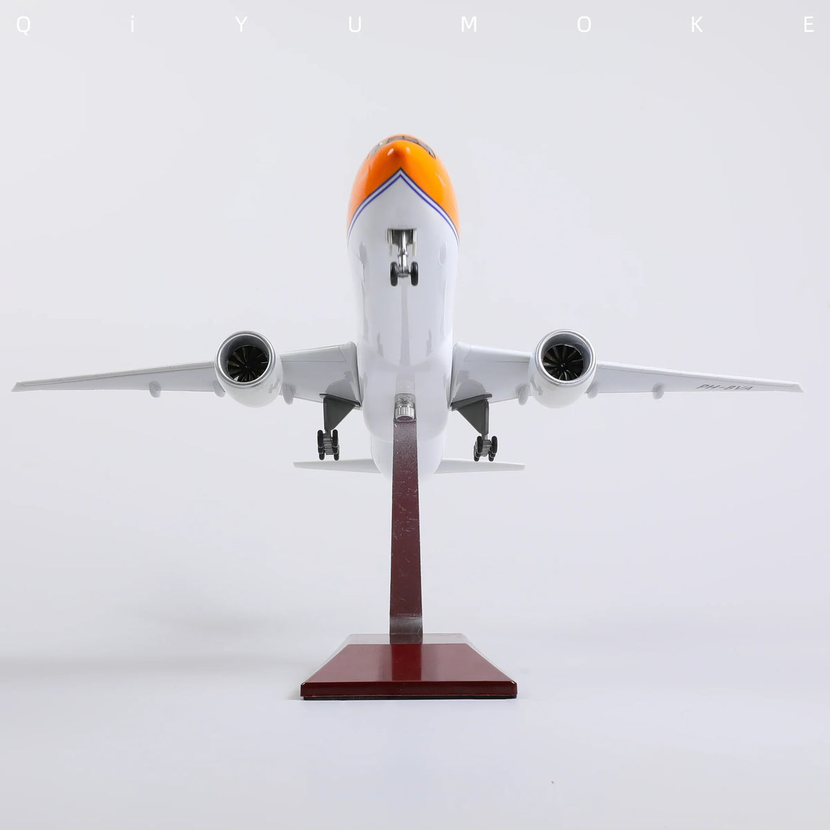 QIYUMOKE Boeing 777-300ER model in orange and white colors, front view on display stand
